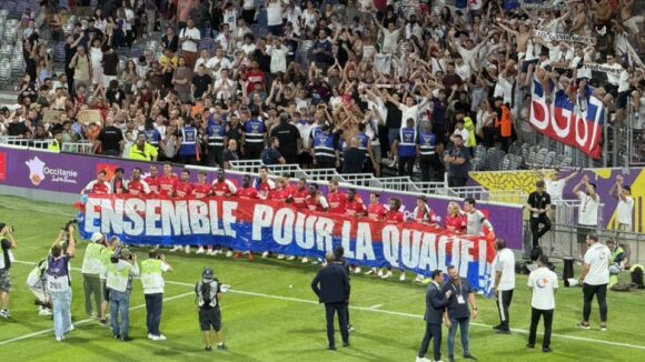 Les joueurs de l'OL posant avec la banderole des supporters lyonnais